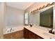 Bright bathroom featuring a soaking tub with tile surround and a dual sink vanity with a large mirror at 10548 Magenta Dr, Noblesville, IN 46060