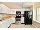 Bright kitchen featuring white cabinets, stainless steel appliances, and a black refrigerator at 10548 Magenta Dr, Noblesville, IN 46060