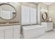 This bathroom showcases a soaking tub, double vanities, granite countertops, and a round mirror above each sink at 10795 Creekbed Cir, Fishers, IN 46038