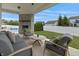 Covered outdoor patio with stone fireplace, comfortable seating, and views of the backyard and pool at 10795 Creekbed Cir, Fishers, IN 46038