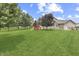 Spacious backyard with a vibrant green lawn, a playset, and mature trees at 1202 Vestman Ct, Greenwood, IN 46143
