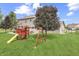 Large, well-maintained backyard with green grass, mature trees, play set, and fenced perimeter at 1202 Vestman Ct, Greenwood, IN 46143