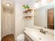 Cozy bathroom with vanity and sink, toilet, and tiled shower area with shelves at 124 Bess Blvd, Pendleton, IN 46064