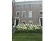 Charming brick townhome featuring a black front door, elegant trim, and lush hydrangea bushes at 12838 Bird Cage, Carmel, IN 46032