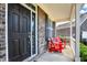 Charming front porch featuring red adirondack chairs and a welcoming dark-colored front door with sidelight at 14095 Northcoat Pl, Fishers, IN 46038