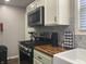 A well-equipped kitchen features a stainless steel stove, microwave, wooden countertops, and white cabinets at 2822 Tindall St, Indianapolis, IN 46203