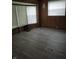 An empty living room features wood paneling, updated floors, and large windows offering natural light at 3216 Memorial N Dr, Elwood, IN 46036