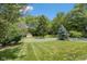 Spacious backyard with manicured lawn, white picket fence, mature trees, and charming playhouse at 6928 Shoals Way, Indianapolis, IN 46237