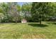 Large backyard with lush lawn, shade trees, and a quaint playhouse for outdoor enjoyment at 6928 Shoals Way, Indianapolis, IN 46237