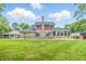 Expansive backyard view of a brick and red two-story house with a well-maintained lawn and mature trees at 1066 N Dogwood Way, Greenfield, IN 46140