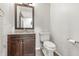 Well-lit half bath with brown cabinets, granite counters, and wood-look tile flooring at 1066 N Dogwood Way, Greenfield, IN 46140