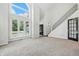 Bright living room with large windows, tall ceilings, carpeted floors, and elegant staircase at 1066 N Dogwood Way, Greenfield, IN 46140