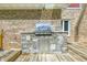 Close-up of an outdoor kitchen with a built-in stainless steel grill and stone surround on a wooden deck at 1066 N Dogwood Way, Greenfield, IN 46140