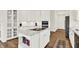 Open kitchen boasting a center island with cooking surface, white cabinets, stainless appliances, and hardwood flooring at 11137 Peppermill Ln, Fishers, IN 46037