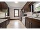 A well-lit kitchen with stainless steel appliances, tile backsplash and dark wood cabinets at 11218 Exchange St, Indianapolis, IN 46259