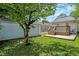 Backyard featuring a detached garage, lush lawn, mature trees, and a wooden deck with access to the house at 1411 N Linwood Ave, Indianapolis, IN 46201