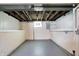 Unfinished basement featuring painted floors, exposed ceilings, and a small window at 1411 N Linwood Ave, Indianapolis, IN 46201