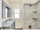 Updated bathroom featuring marble countertop, gray vanity, and tiled shower with built-in shelves at 1411 N Linwood Ave, Indianapolis, IN 46201