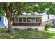 A charming brick home boasts a brick and white porch, complemented by a lush green lawn and mature trees at 1411 N Linwood Ave, Indianapolis, IN 46201