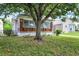 Charming home with a brick and white porch, set amidst a green lawn and framed by a mature shade tree at 1411 N Linwood Ave, Indianapolis, IN 46201
