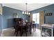 Cozy dining room with blue walls, a wooden table set for six, and natural light from a window at 15372 Black Gold Ct, Noblesville, IN 46060
