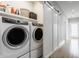 Well-lit laundry room featuring front-load washer and dryer, sliding barn door, and storage shelves at 1610 N Alabama St, Indianapolis, IN 46202