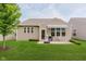 Rear view of house, with a patio, grill, and small awning overlooking a lush backyard at 16573 Grappa Trl, Fishers, IN 46037