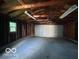 Wide view of a garage interior with wood beams and a metal garage door at 2914 Baltimore Ave, Indianapolis, IN 46218