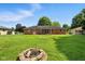 Large backyard featuring a brick home, well-maintained lawn, and a charming fire pit for outdoor gatherings at 3504 White River Ct, Anderson, IN 46012