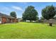 Expansive backyard featuring lush green grass, mature trees, playset, and partial view of the home's exterior at 3504 White River Ct, Anderson, IN 46012