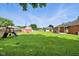 Vast backyard with a playset, shed, and view of the home's rear exterior and neighboring properties at 3504 White River Ct, Anderson, IN 46012