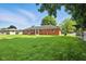 Spacious backyard with a well-manicured lawn, mature trees, and a view of the brick home exterior at 3504 White River Ct, Anderson, IN 46012