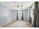 Bedroom with ceiling fan, plush carpet, gray walls, and multiple windows with gray curtains at 3504 White River Ct, Anderson, IN 46012
