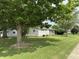 View of a cozy single-story house with a large tree in the front yard and a well-maintained lawn at 411 N 18Th St, Noblesville, IN 46060