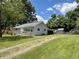 A cozy single-story home with a welcoming entrance ramp, surrounded by a green lawn and mature trees at 411 N 18Th St, Noblesville, IN 46060