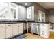 Kitchen featuring white cabinets, stainless steel dishwasher, black countertops, and a view into the breakfast nook at 4130 N Meridian St, Indianapolis, IN 46208