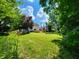 A serene backyard featuring a wooden deck and lush green lawn with mature trees and blue sky at 4536 Clayburn Dr, Indianapolis, IN 46268