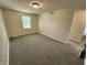 A well-lit bedroom with neutral paint and carpet is shown with a light fixture, window, and trimmed baseboards at 4536 Clayburn Dr, Indianapolis, IN 46268