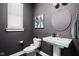 Stylish powder room featuring dark gray walls, a pedestal sink, and a round mirror at 630 Dorman St, Indianapolis, IN 46202