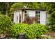 Charming shed in a beautifully landscaped backyard, featuring white windowed doors and natural shade from trees at 6379 Monitor Dr, Indianapolis, IN 46220