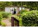 Exterior view of white windowed doors shed in a lush landscaped backyard with stone walkway and trimmed green bushes at 6379 Monitor Dr, Indianapolis, IN 46220