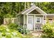 Exterior of a charming shed with black and white chair, white door, and cottage-core landscaping in the backyard at 6379 Monitor Dr, Indianapolis, IN 46220