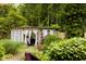 Exterior view of the backyard shed featuring white windowed doors and curtains in a lush landscaped backyard at 6379 Monitor Dr, Indianapolis, IN 46220
