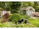 Exterior view of backyard featuring a charming shed, lush greenery, black flower pots, and landscaping at 6379 Monitor Dr, Indianapolis, IN 46220