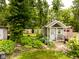 View of the garden shed with a covered porch, surrounded by lush greenery and a stone pathway at 6379 Monitor Dr, Indianapolis, IN 46220