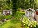 The backyard features two garden sheds, surrounded by lush greenery and stone pathways at 6379 Monitor Dr, Indianapolis, IN 46220