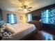 Bedroom with a wooden bed frame, ceiling fan, dresser, hardwood floors, and natural light at 6546 Derbyshire Rd, Indianapolis, IN 46227