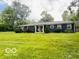 Ranch-style home with a large front yard, a covered porch, and mature trees at 6546 Derbyshire Rd, Indianapolis, IN 46227