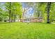 Large, grassy backyard with mature trees surrounds a brick home featuring a cozy sunroom extension at 10104 Sycamore Ln, Indianapolis, IN 46239
