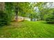 Lush backyard features mature trees surrounding a brick home with a sprawling green lawn, offering a private retreat at 10104 Sycamore Ln, Indianapolis, IN 46239